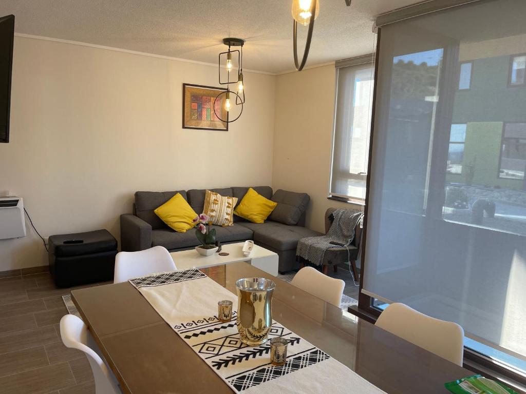 ein Wohnzimmer mit einem Sofa, einem Tisch und Stühlen in der Unterkunft Puerto Montt apartamento en playa Pelluco in Puerto Montt