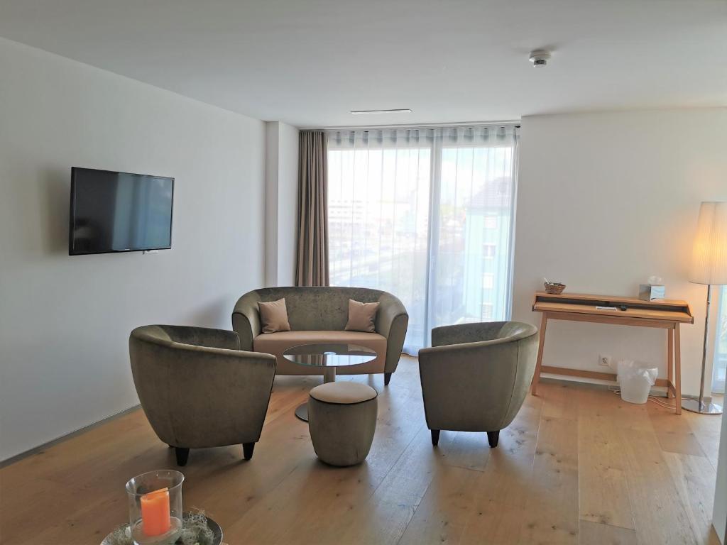 a living room with chairs and a couch and a tv at Hotel AVA in Sempach Station