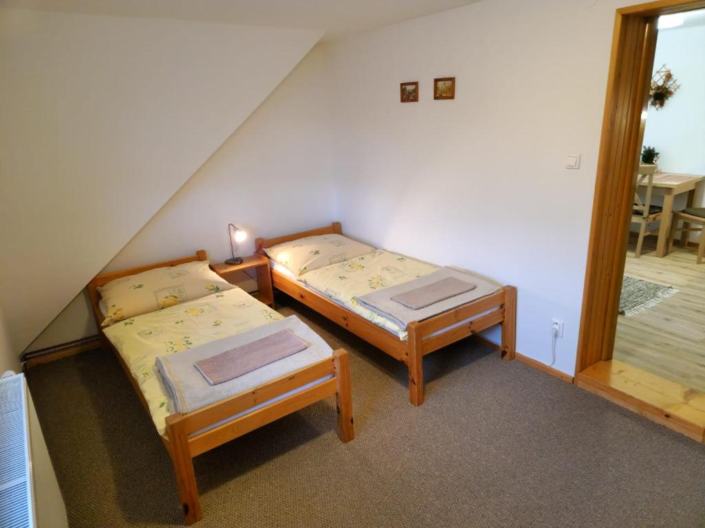 two twin beds in a room with a staircase at Apartmány Grobarčík in Zuberec