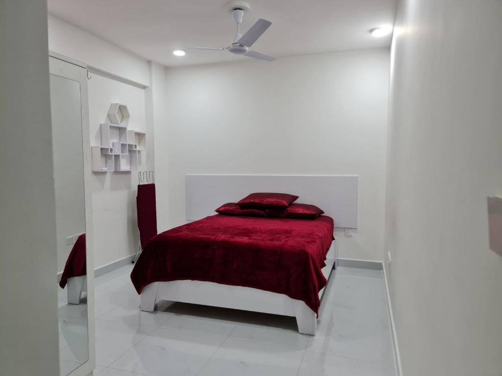 Cette chambre blanche comprend un lit avec une couverture rouge. dans l'établissement Resting View, à Malé
