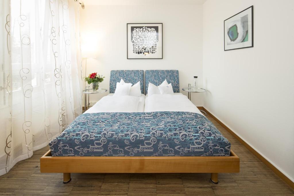a bedroom with a bed with a blue and white bedspread at Business & Art Hotel Markgraf in Emmendingen