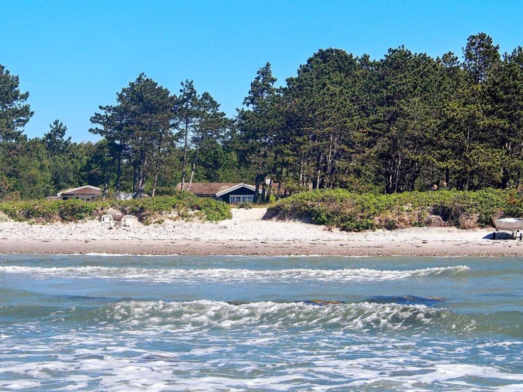 a beach with a house and trees in the background at Holiday home Nykøbing Sj II in Tjørneholm