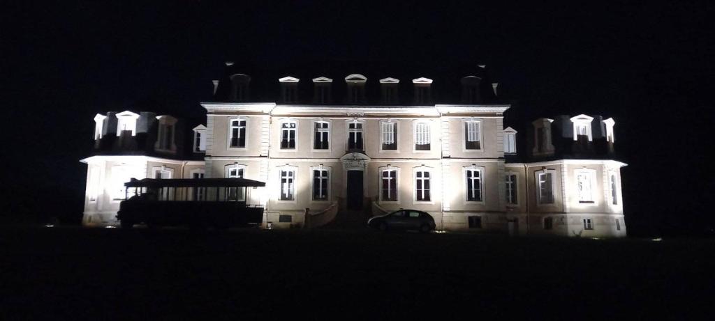 Une grande maison blanche éclairée la nuit dans l'établissement Château de la Bouchatte chambre les Roses, à Chazemais