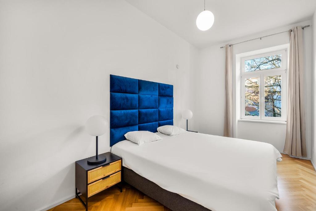 Schlafzimmer mit einem großen Bett mit blauem Kopfteil in der Unterkunft Vienna Chic Residences #Suite 7 in Wien