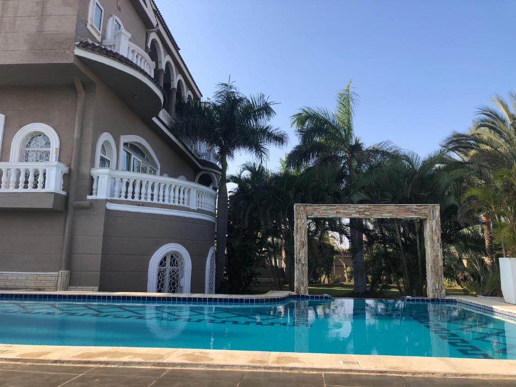 une maison avec une piscine en face d'un bâtiment dans l'établissement Condo in a Private Resort setting King Maryout Alamriyah Governorate Egypt Comes with an outdoor private infinity swimming pool with a large garden Borg Alarb International Airport is 15 minutes, à Alexandrie
