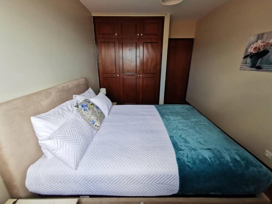 Dormitorio pequeño con cama con sábanas y almohadas blancas en Alegria A en Funchal