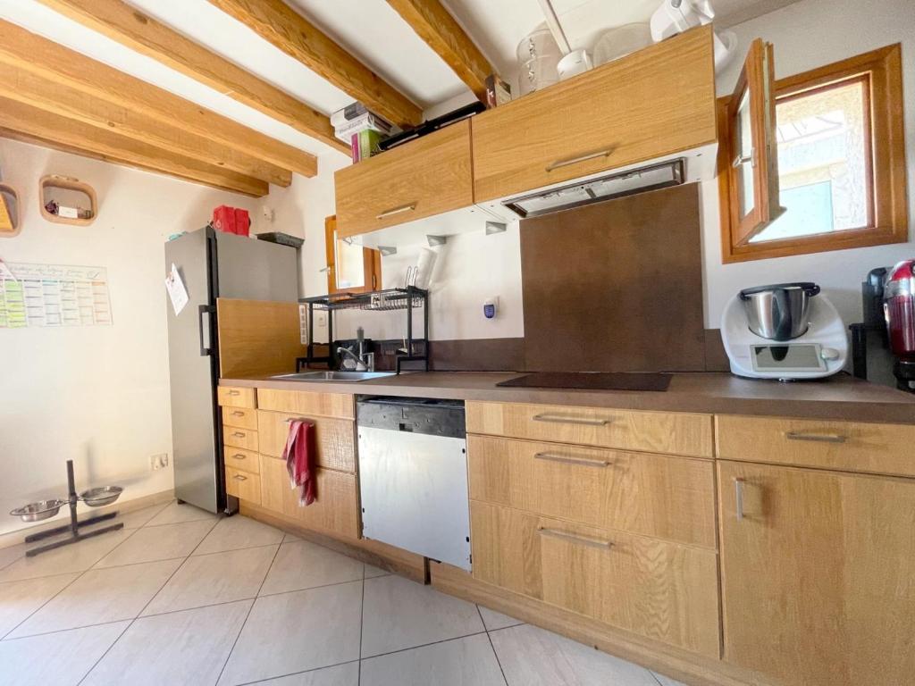 kuchnia z drewnianymi szafkami i lodówką w obiekcie Chalet des Grangettes avec jardin, sauna et Appli Roadbook - Huez w mieście LʼHuez