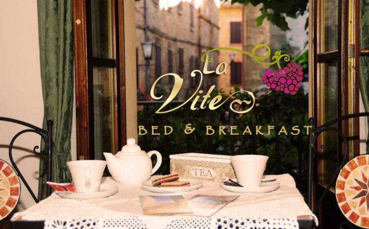 uma mesa com chávenas e pires e um sinal de vida cama e pequeno-almoço em B&B Camere La Vite em Pienza