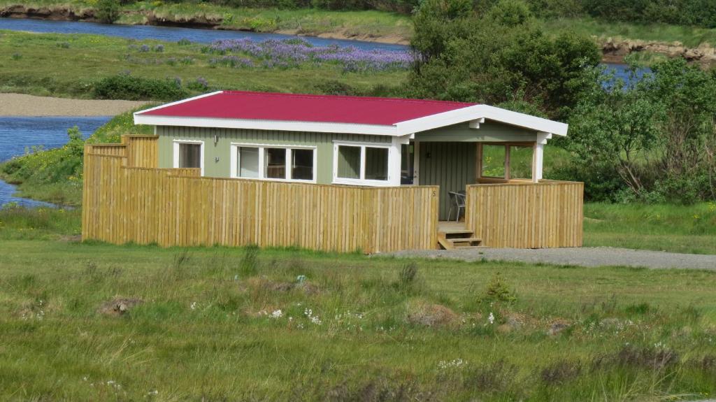 una pequeña casa con techo rojo en un campo en Hvammur 5 with private hot tub, en Drangsnes