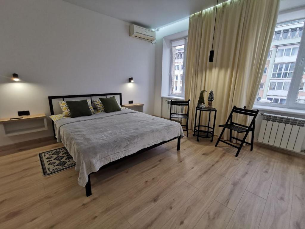 um quarto com uma cama grande e 2 janelas em Soborna Apartment em Rivne