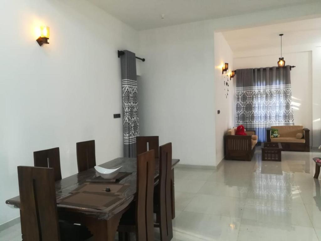 a dining room with a table and a living room at Wood Land Villa in Ambalantota