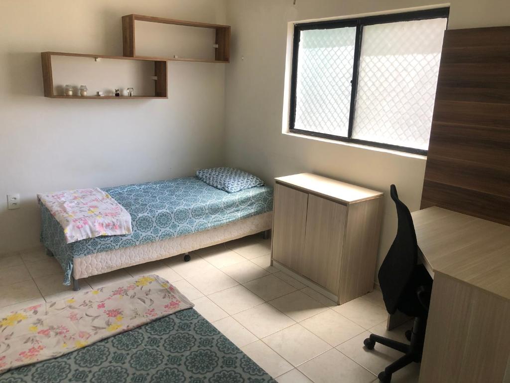 a bedroom with a bed and a desk and a window at Verão on in Cabedelo