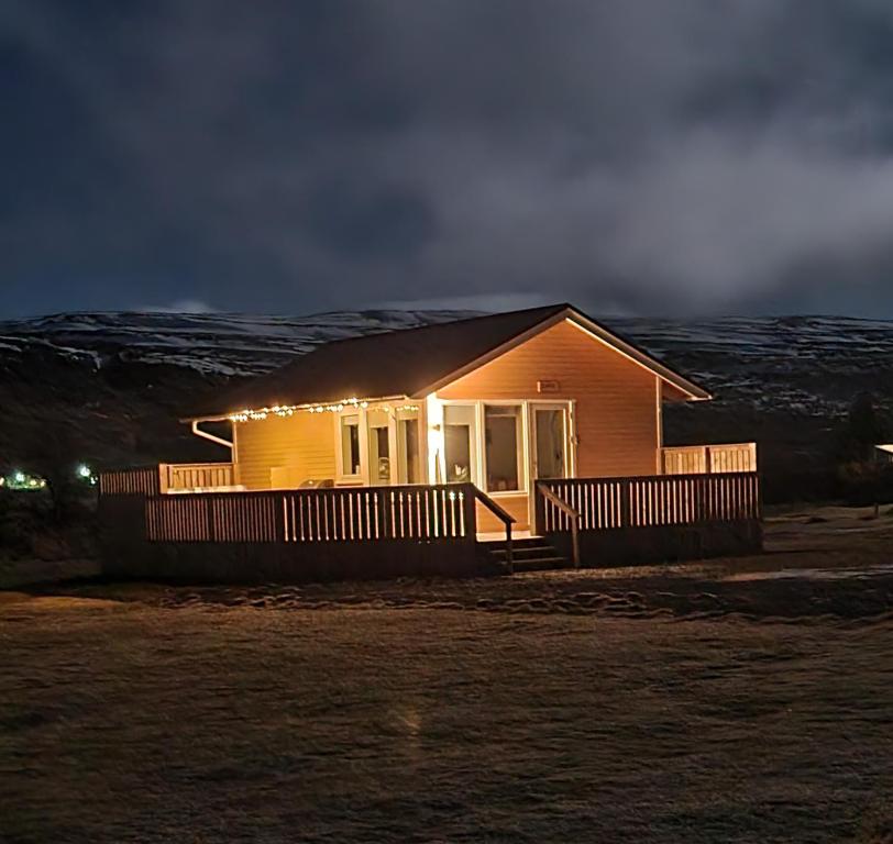 a small house with lights on the front of it at Hvammur 2 Bjarg with private hot tub in Drangsnes