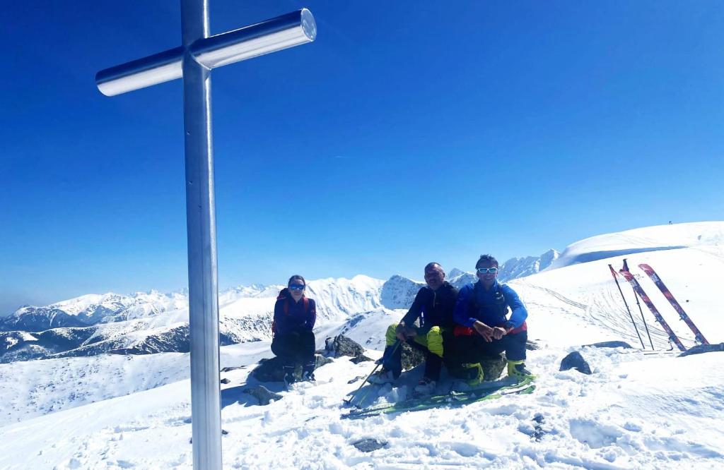a group of people sitting in the snow next to a cross at Apartmány Grobarčík in Zuberec