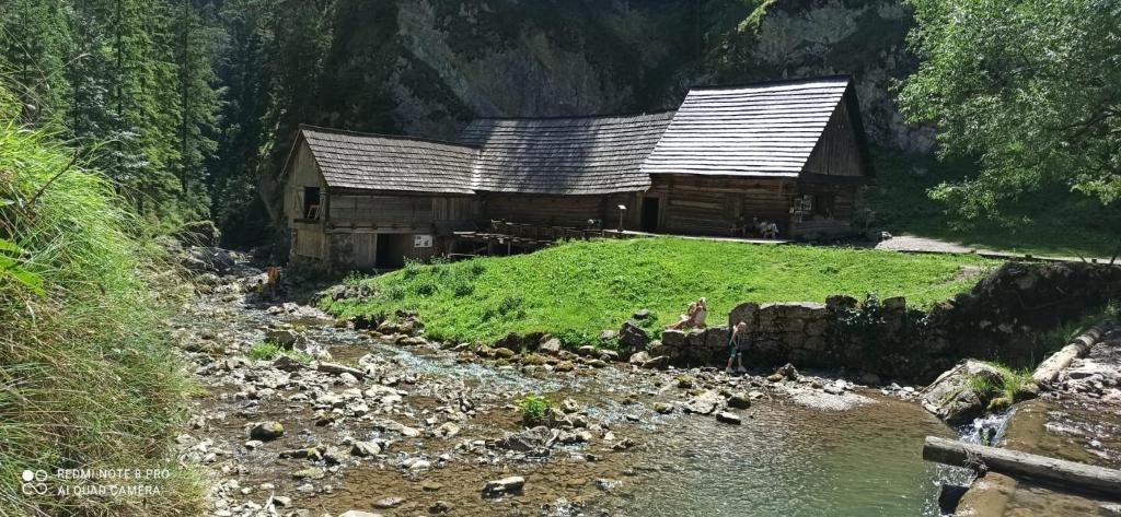 an old cabin on a hill next to a river at Apartmány Grobarčík in Zuberec