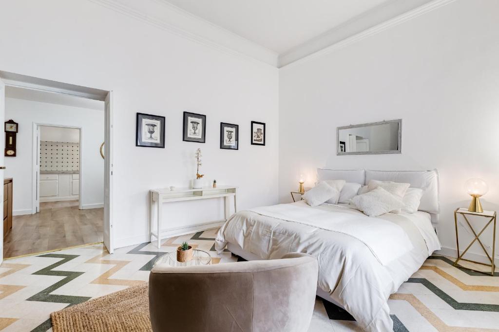 a white bedroom with a bed and a chair at Living Rome Repubblica apartment in Rome