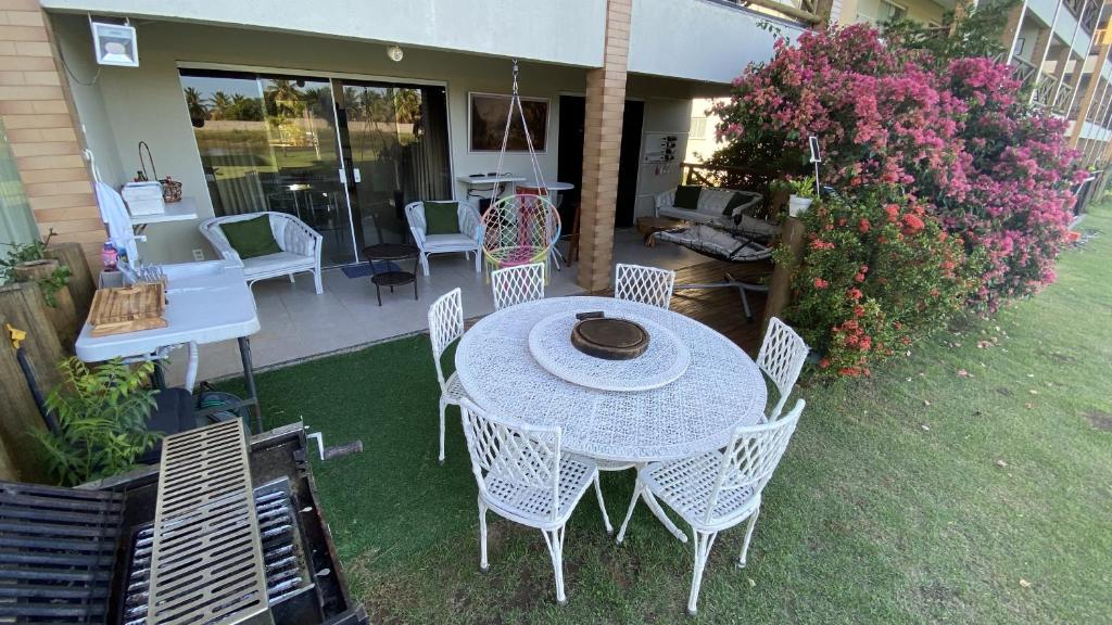 a patio with a table and chairs on the grass at Apartamento térreo confortável no Condomínio Villa das Águas in Estância