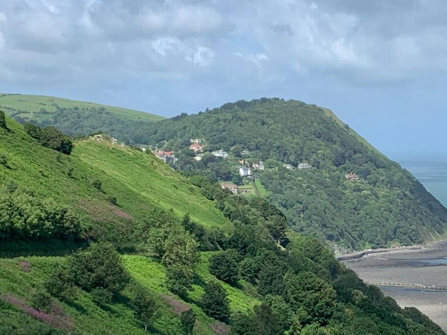 a green hill with a town on top of it at Lovely flat located in heart of Lynton. in Lynton