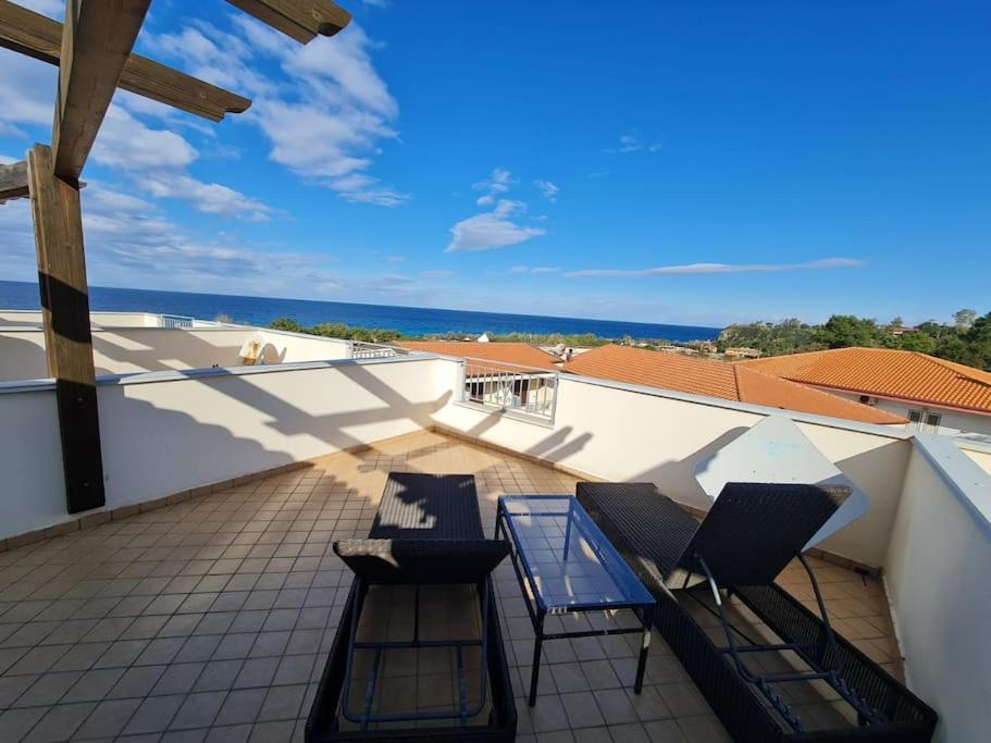 - Balcón con 2 sillas y mesa de cristal en Zambrone Beach Villas, en Zambrone