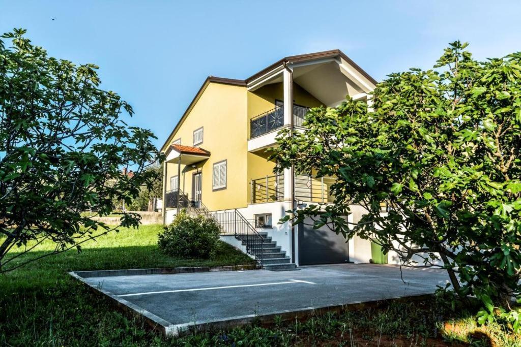 żółty dom ze schodami i drzewami przed nim w obiekcie Apartments Lia-Jolie w mieście Umag
