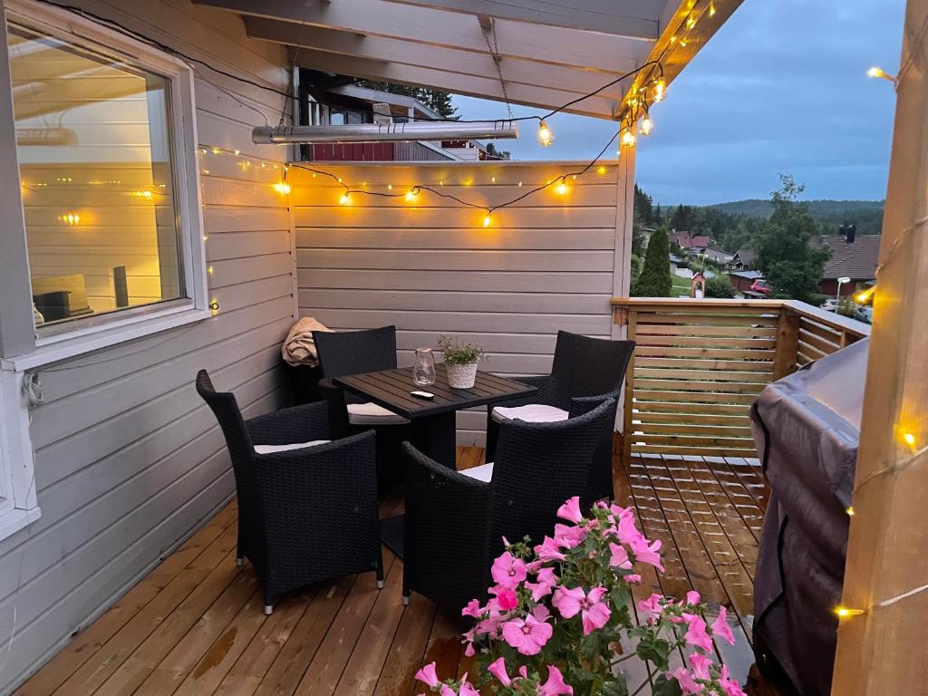 a patio with a table and chairs on a deck with lights at Privat leilighet nær byen og marka in Lillehammer
