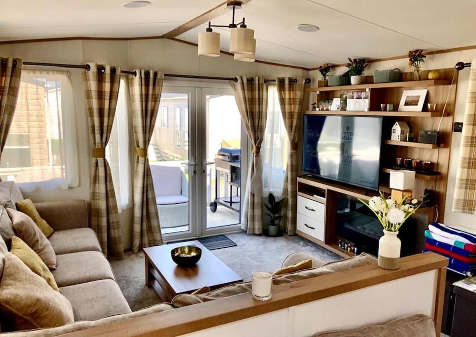 a living room with a couch and a tv at Seaview Park Premium Static Caravan Whitstable in Whitstable