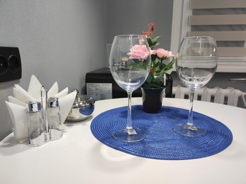 una mesa con dos copas de vino y un jarrón con flores en Бизнесс Апартаменты Центр Уральск en Oral