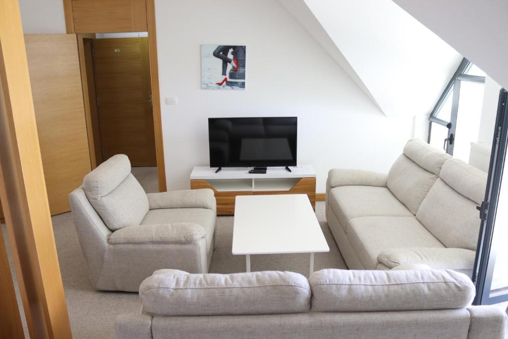 uma sala de estar com um sofá e duas cadeiras e uma televisão em Apartmani Vlašić-Petrol em Travnik