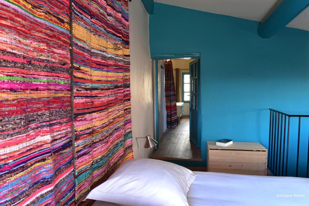 Les Maisons Mado في فيناسك: غرفة نوم مع بطانية ملونة على الحائط