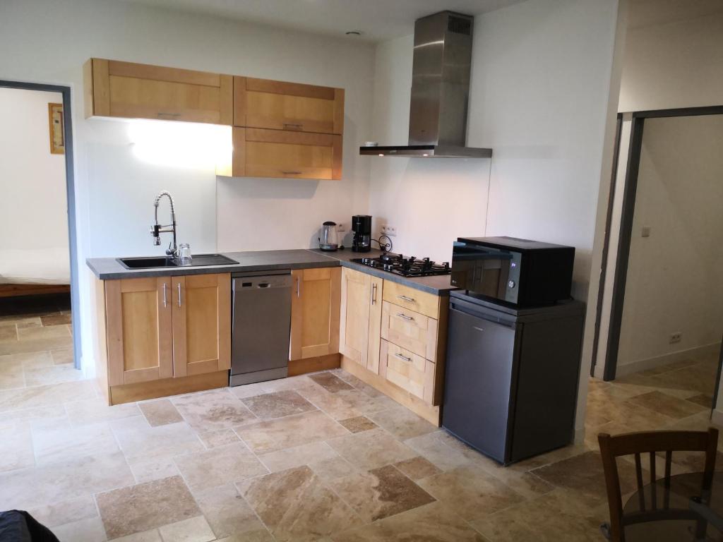 a kitchen with wooden cabinets and a sink and a dishwasher at Appartement entier dans dépendance in Saint-Morillon