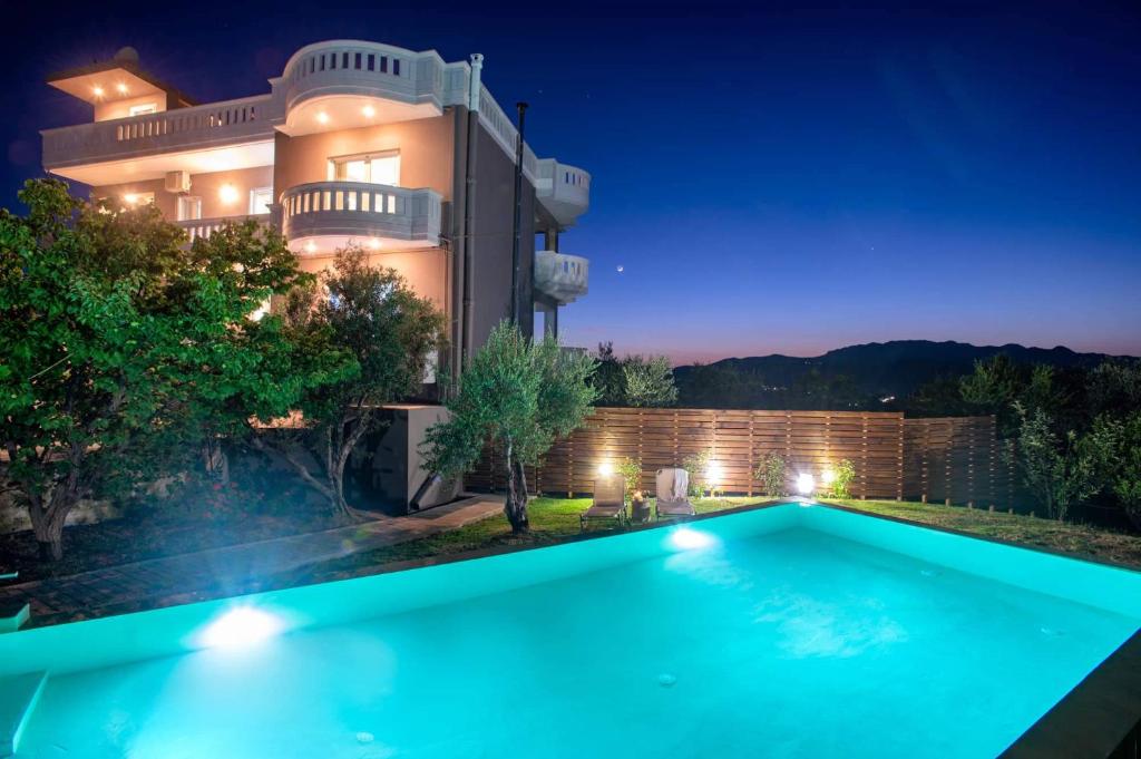 a villa with a swimming pool at night at Majestic Villa-Apartments in Darmarochori