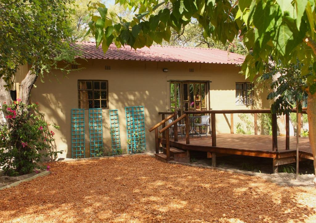 a house with a wooden deck in front of it at Acacia Cottage in Maun