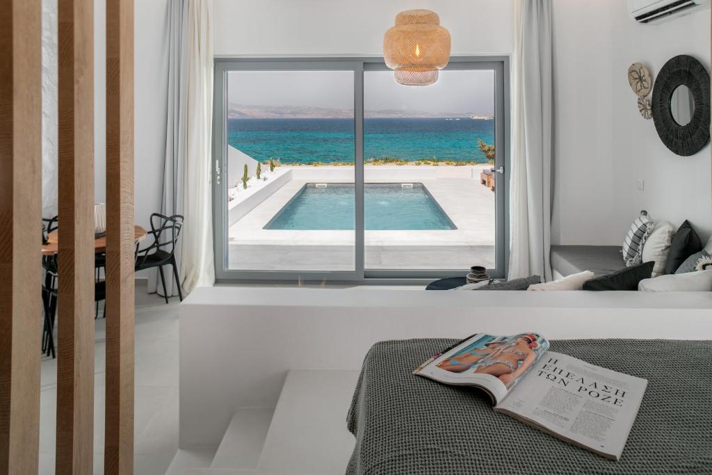 1 dormitorio con vistas a la piscina a través de una ventana en Seanfinity Beachfront Suites, en Mikri Vigla