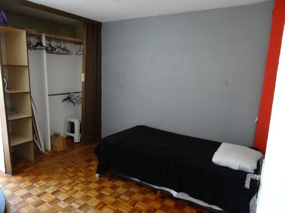 a bedroom with a bed with a black bedspread and a room at Departamento en Buenavista EXCELENTE UBICACIÓN in Mexico City