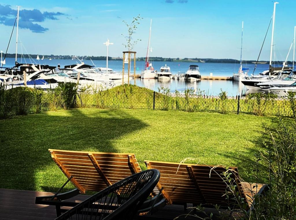 dos sillas sentadas en un césped con barcos en el agua en Apartament Morsa w Nautica Resort, en Giżycko