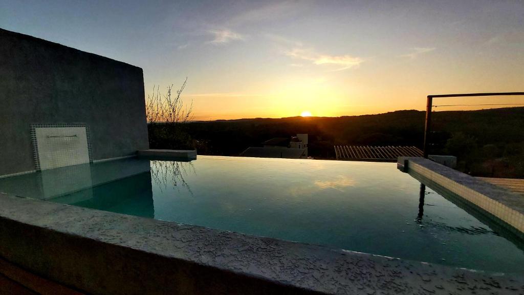 a swimming pool with the sunset in the background at La Ñata in Villa Giardino