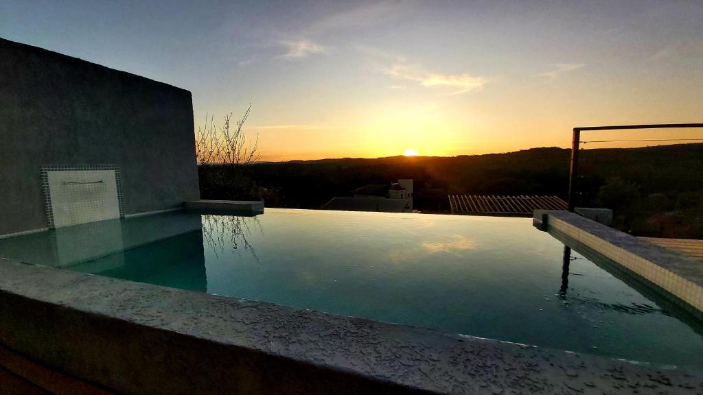 una piscina con puesta de sol en el fondo en La Ñata en Villa Giardino