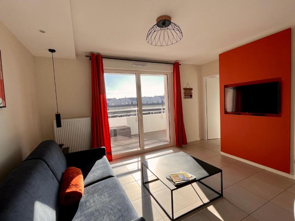 a living room with a couch and a tv at L'intemporel plage - Malo'Cation in Dunkerque