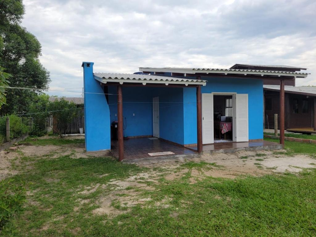 ein blaues Haus mit einer weißen Tür im Hof in der Unterkunft Casa temporada praia da galheta 3 in Laguna