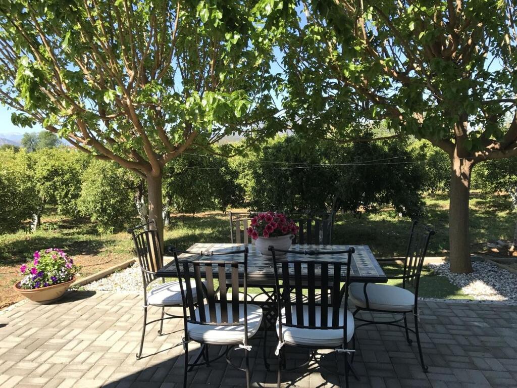 une table et des chaises sur une terrasse sous un arbre dans l'établissement Villa apartment with private garden near the beach, à Drepano