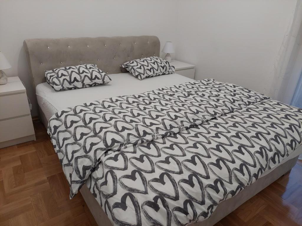 ein Bett mit einer schwarzen und weißen Bettdecke und 2 Kissen in der Unterkunft Sunrise Apartments sa garažom in Banja Luka