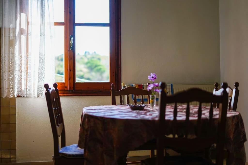 une table à manger avec des chaises et une fenêtre dans l'établissement Traditional cozy residence in Lafkos, Pelion, à Lafkos