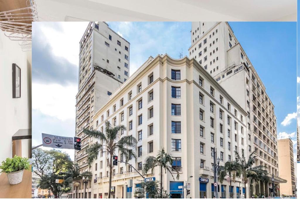 un gran edificio blanco en una calle de la ciudad con palmeras en Jacques Pilon estúdio 425, en São Paulo