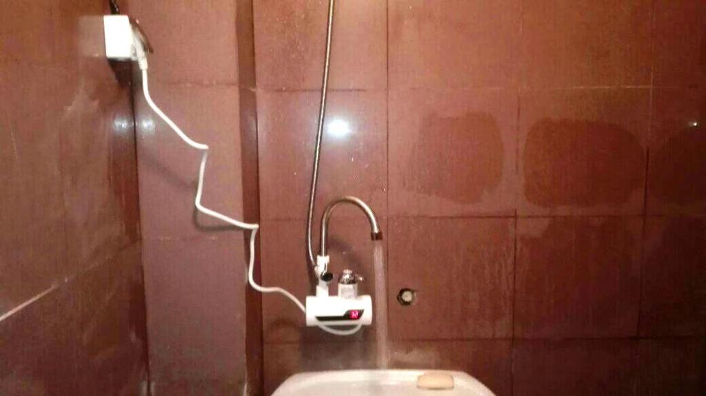 a bathroom with a shower with a hose on the wall at Стаи на пъпа на Варна, входа на Морската градина in Varna City