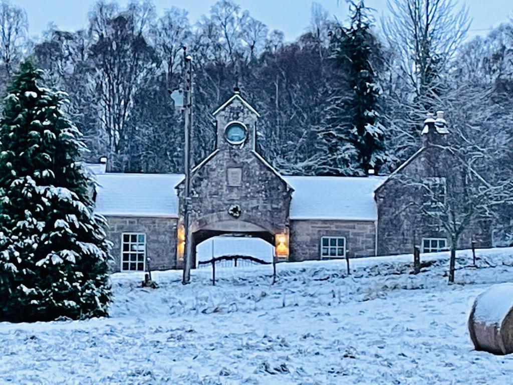 亞伯樂的住宿－Coachmans Cottage，一座大石头建筑,在雪中设有钟楼