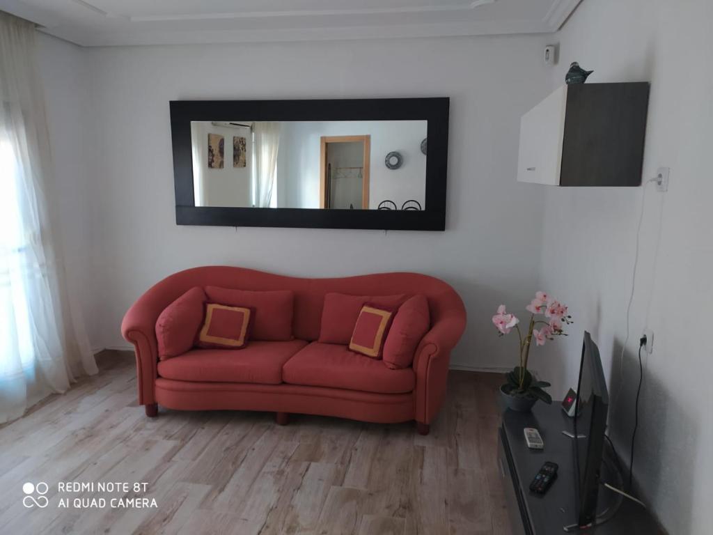 un sofá rojo en la sala de estar con espejo en Tu Casa en Albacete, en Albacete