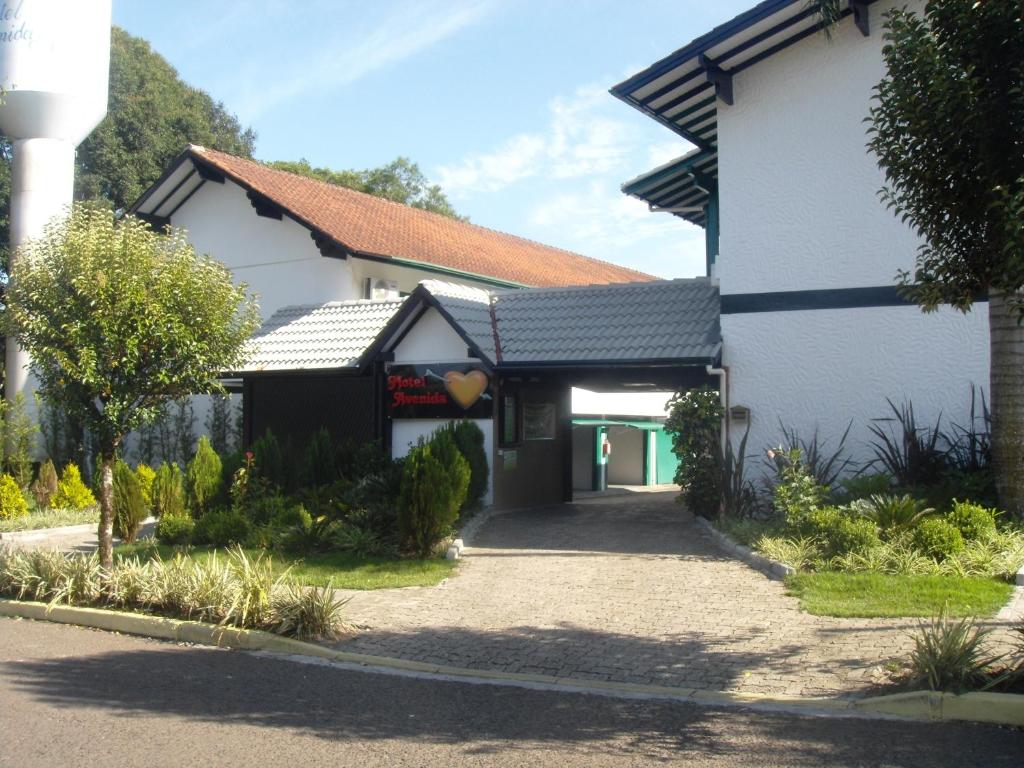 ein weißes und schwarzes Gebäude mit Auffahrt in der Unterkunft Motel Avenida (Adult Only) in Gramado