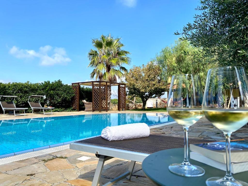 zwei Gläser Wein auf einem Tisch neben einem Pool in der Unterkunft Villa Rita - Puglia Mia Apartments in Antonelli