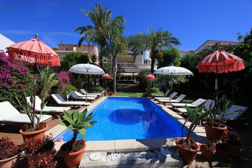 einen Pool mit Liegestühlen und Sonnenschirmen in der Unterkunft Villa Sitges Palm Garden: 5 minutes walking from beach. Amaizing Garden/Outdoor in Sitges