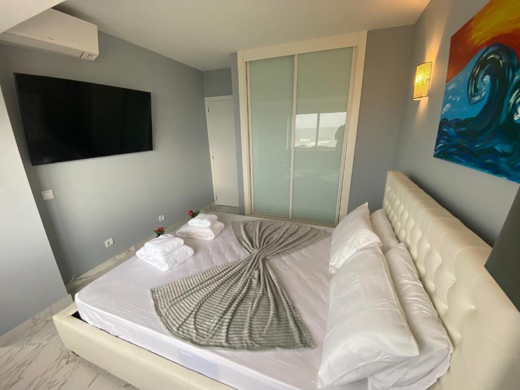 a bedroom with a white bed with a tv on the wall at SEA FRONT in Armação de Pêra